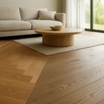 Herringbone parquet in warm oak beside matte wide-plank oak flooring in a modern living room under natural daylight.